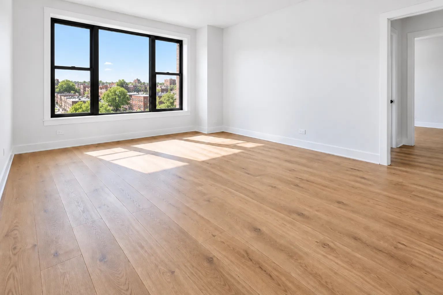A freshly finished room with new plank flooring, white walls and baseboards