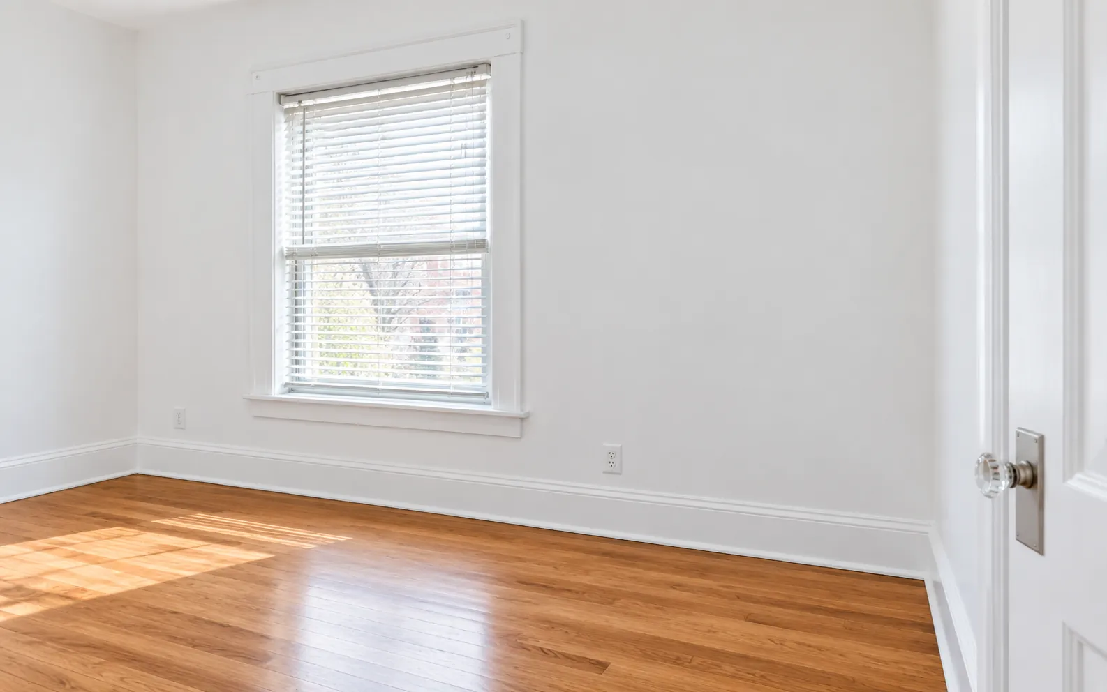 A clean, empty, rent-ready room with refinished floors